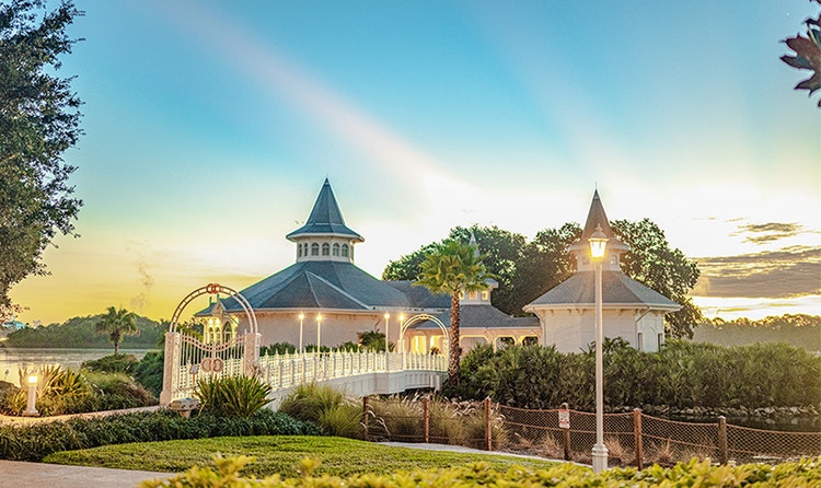 Lamps light the way across a bridge to Disney’s Wedding Pavilion at sunset
