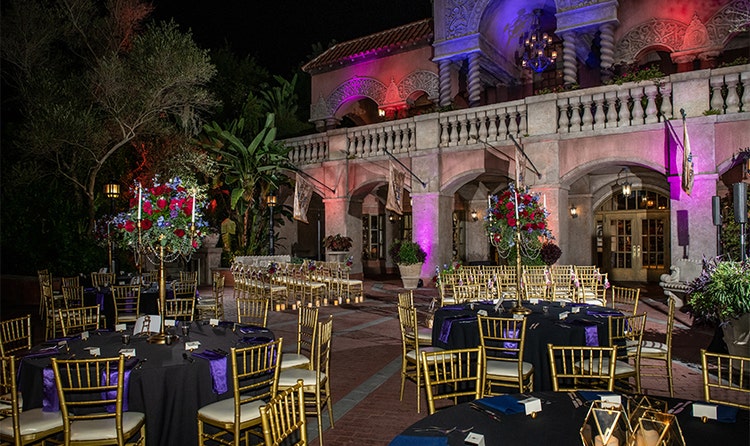 Several round tables surrounded by chairs and decorated with floral arrangements