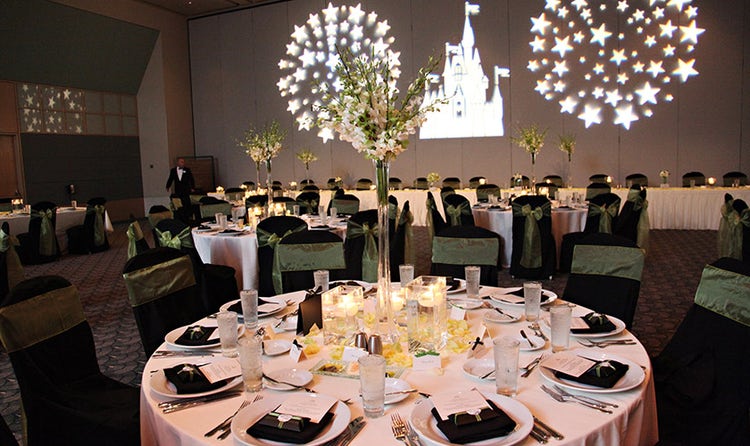 Projections of Cinderella Castle and fireworks on a wall in a room filled with large tables