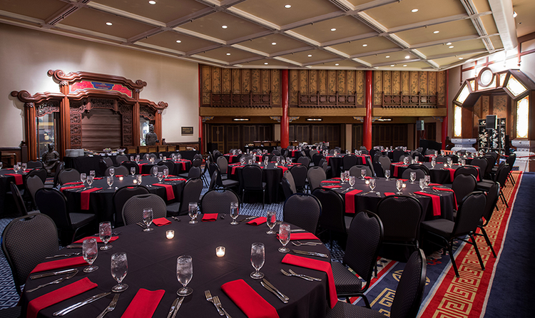 A wedding banquet room with Chinese inspired décor, furnished with several tables and chairs