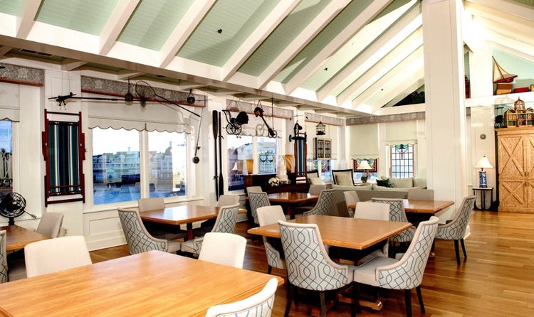 A dining area with tables and chairs facing windows overlooking Disney's BoardWalk