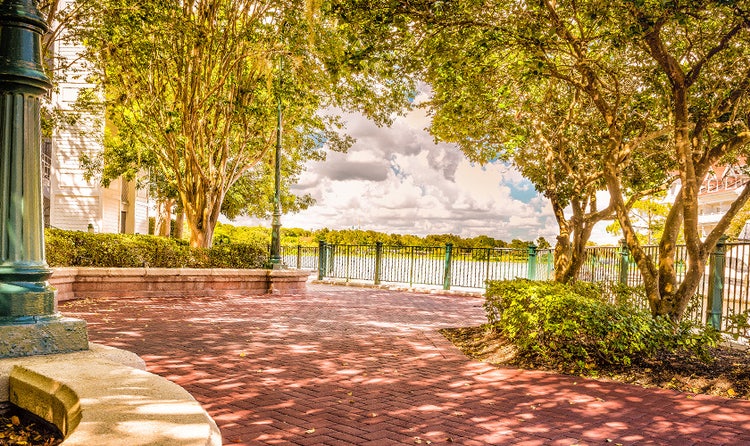 A shady brick path with a cast iron guardrail looks out over the water