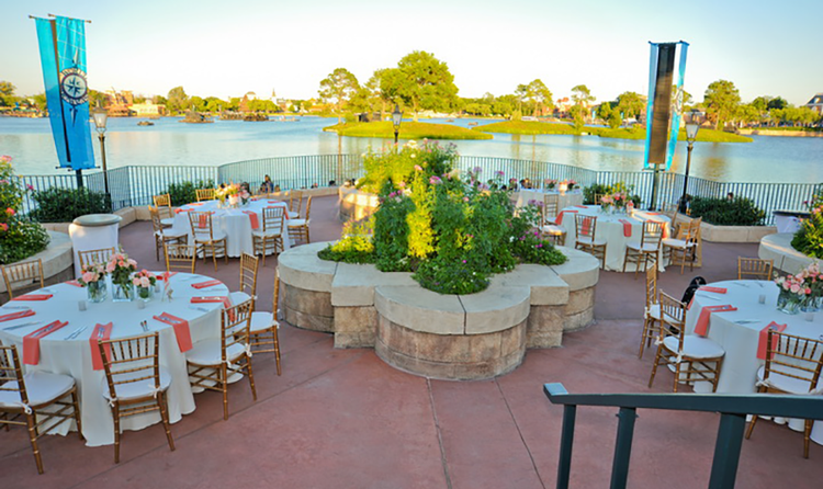 Several tables and chairs decorated for a wedding at Terrace des Fleurs, a large terrace overlooking Crescent Lake at EPCOT