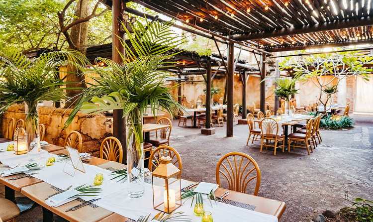 A reception area set up beneath a covered courtyard featuring decorative palm fronds and glowing lanterns