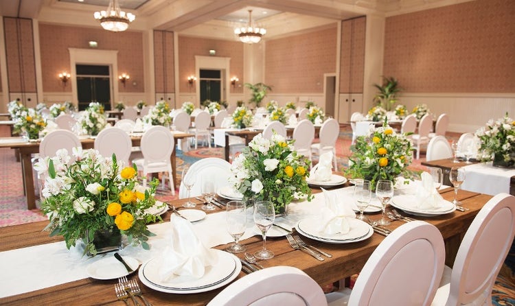 Rows of set tables decorated with flower centerpieces in a ballroom at Disney's BoardWalk Inn