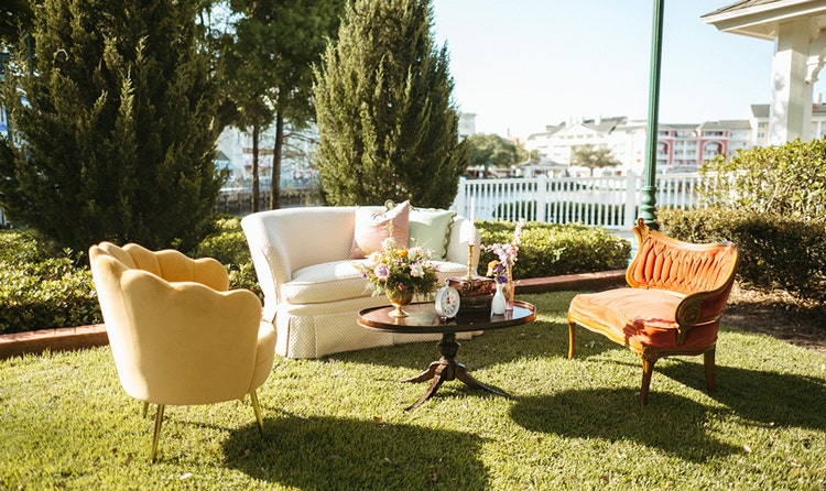 A coffee table, floral arrangements, a sofa and 2 armchairs on a lawn at a wedding cocktail hour at Seabreeze Point