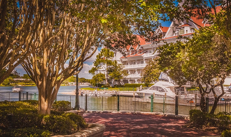 The Sago Cay venue reveals shading trees and a brick path overlooking the Seven Seas Lagoon and Disney's Grand Floridian Resort & Spa