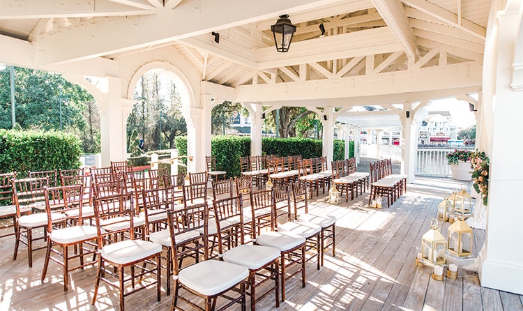 A deck with many rows of chairs and decorative lanterns holding candles