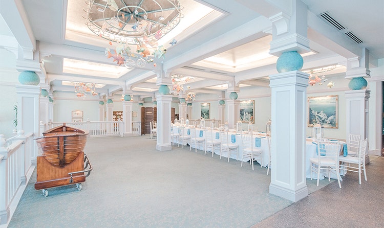 A rowboat rests near a railing in a room featuring a long dining table and many chairs