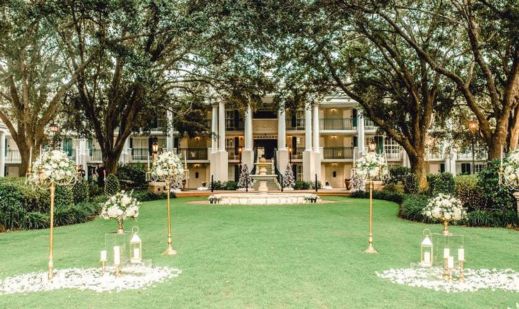 A lawn with flower bouquets surrounded by oak trees facing Oak Manor in Disney’s Port Orleans – Riverside