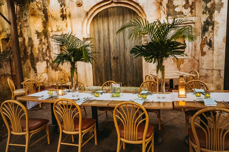 A reception area set up beneath a covered courtyard featuring decorative palm fronds and glowing lanterns.