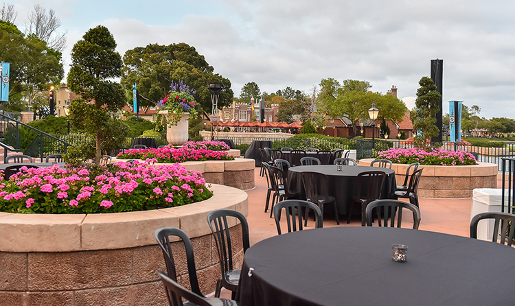 Several tables and chairs arranged between the flower beds at Terrace des Fleurs, a large terrace at EPCOT