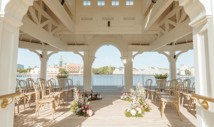 A wedding ceremony venue in a gazebo at Seabreeze Point with bentwood chairs and floral arrangements lining the aisle, looking out over Crescent Lake