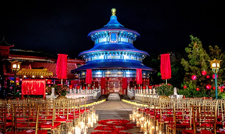 Rows of chairs with lit candles lining an aisle of rose petals at the China Pavilion