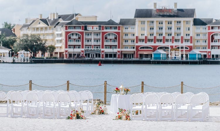 A round table on a beach facing a body of water and Disney’s BoardWalk