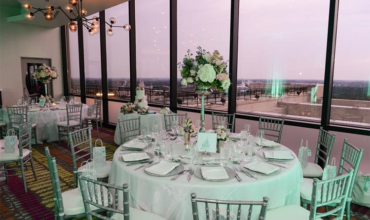 Round tables with many place settings next to tall windows