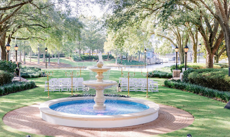A large water fountain in front of rows of chairs surrounded by oak trees in Disney’s Port Orleans Riverside