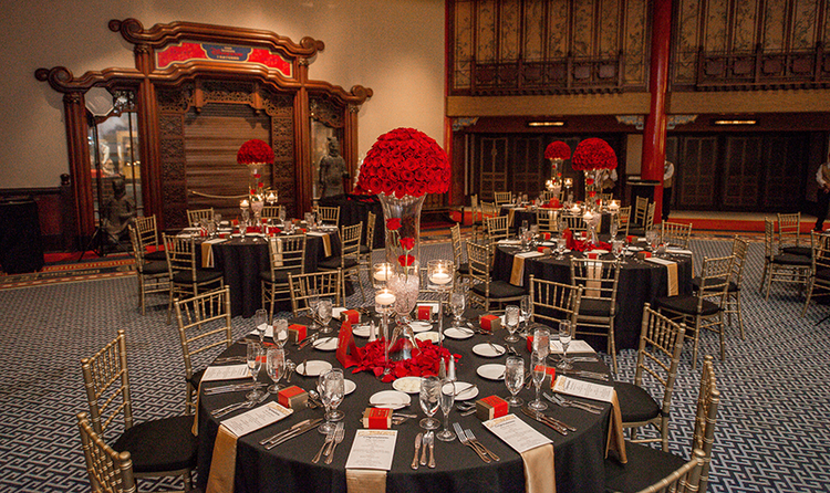 A wedding banquet room with Chinese inspired décor, furnished with several tables and chairs