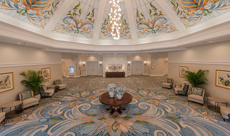 A grand lobby with a floral chandelier and stained-glass windows at a ballroom at Disney's Grand Floridian Convention Center