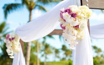 A wedding ceremony archway draped with fabric and floral