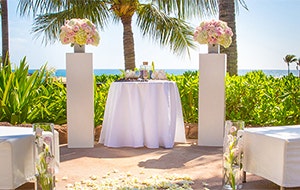 Large benches pointed towards an altar decorated with bouquets of flowers at a beach
