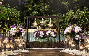Several lit candles line an aisle along with several bouquets of flowers