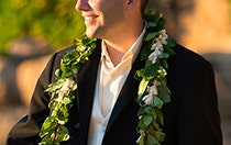A groom in a suit wearing a traditional Hawaiian maile lei