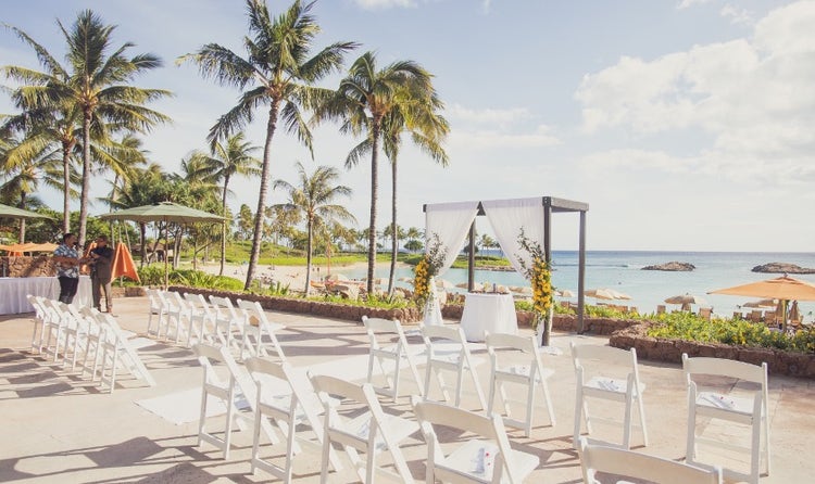 Chairs lined up along a beach overlooking Ko Olina’s lagoon and surrounded by palm trees
