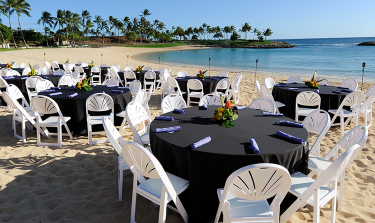 Round tables and chairs arranged on a beach