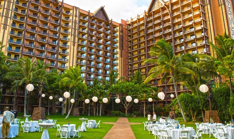 Tables and chairs set up on a lawn under lanterns in front of Aulani, A Disney Resort & Spa