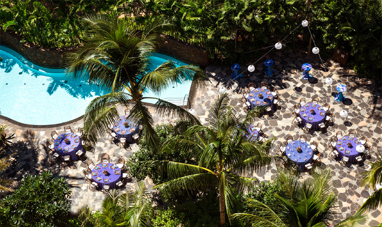 A winding pool and a patio holding several round tables
