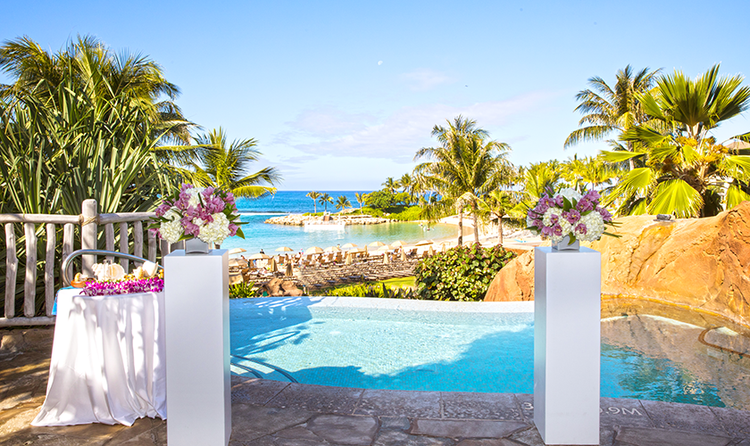 Two podiums stand before a body of water near large palm trees