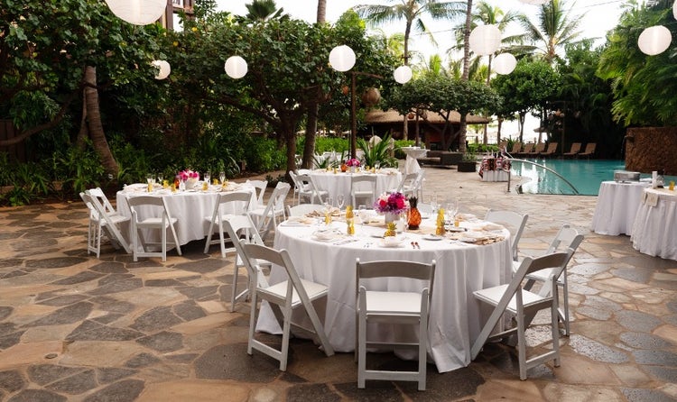 Tables and chairs set up alongside Wailana Pool with hanging lanterns and flower centerpieces