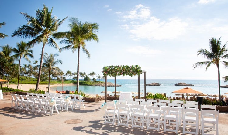 Chairs lined up along a beach overlooking Ko Olina’s lagoon and surrounded by palm trees