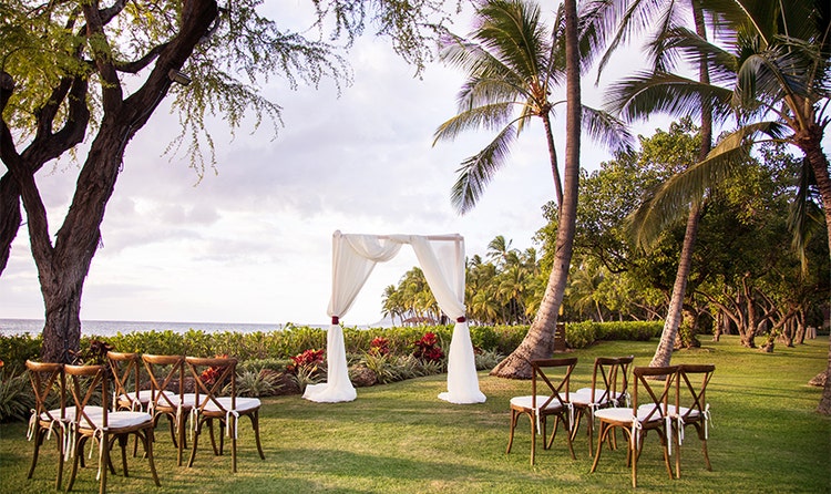 Nine chairs face a small altar near palm trees
