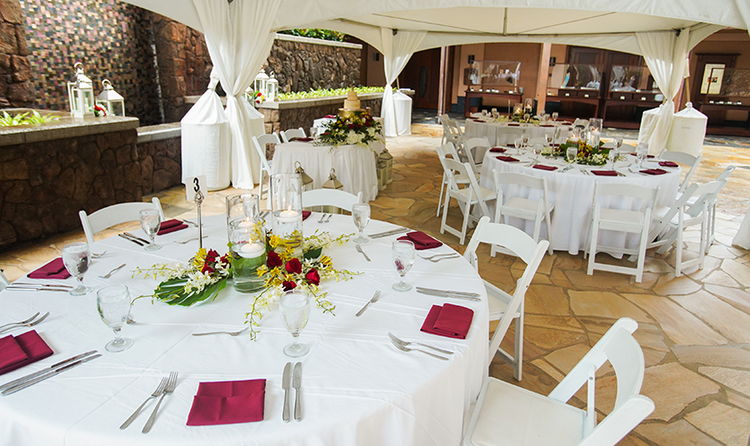 Wedding table settings beneath a large cabana, in a resort courtyard paved in stone