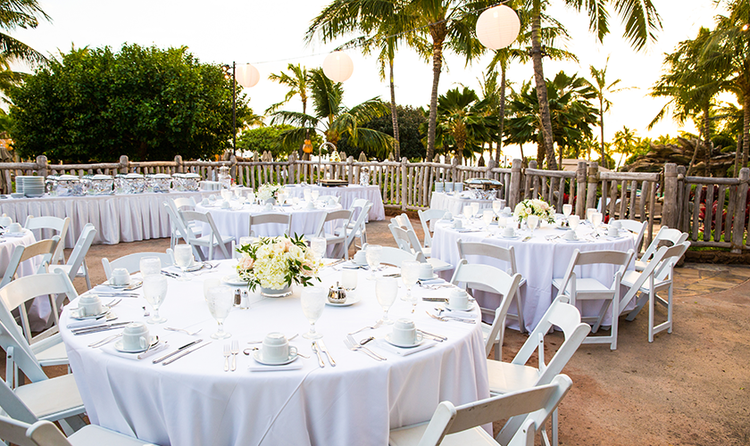 A buffet table and a few round tables with floral center pieces on an outdoor patio