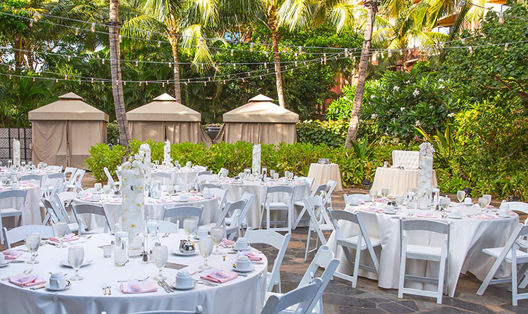 Strings of lights draped over several round tables arranged for a wedding reception