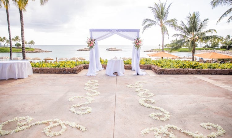 Flower petals set up in decorative patterns on the ground leading to a table facing the beach