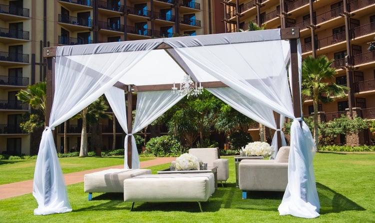 An outdoor seating area set up beneath a canopy featuring armchairs and ottomans