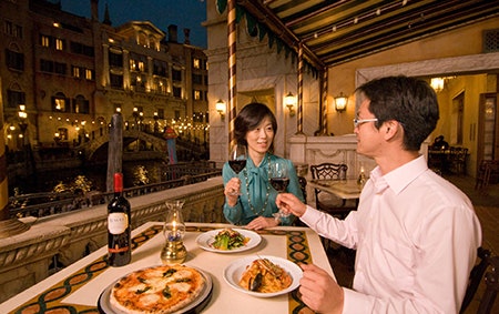 Two newlyweds dining and toasting their wine glasses at an Italian restaurant at Tokyo Disney Resort
