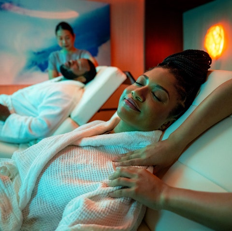 A man a woman with their eyes closed getting a massage on reclining massage chairs