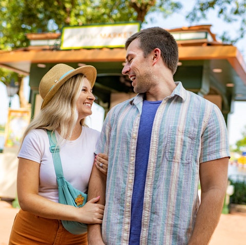 A woman holding a man’s arm while he smiles back at her at Epcot