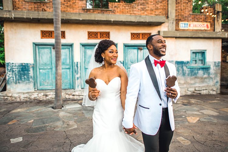 A bride and groom posing with Mickey Mouse ice cream bars in Harambe Village