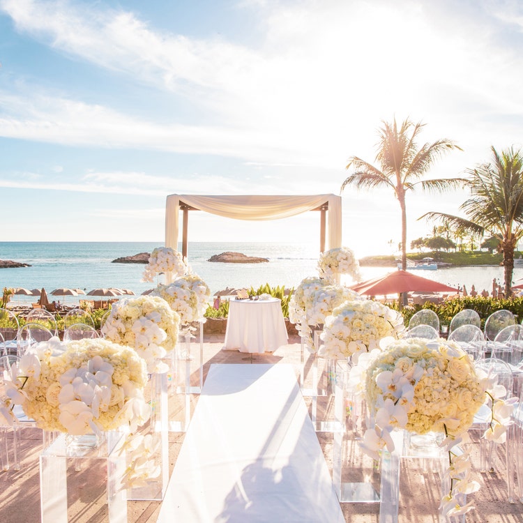 A wedding ceremony set up with flowers and chairs overlooking the ocean at Aulani, a Disney Resort & Spa