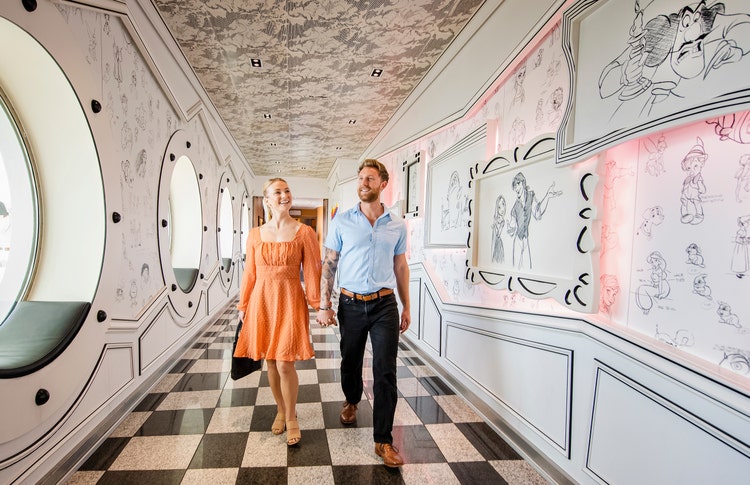 A couple walking through the entrance of Animator's Palate filled with sketches of Disney characters