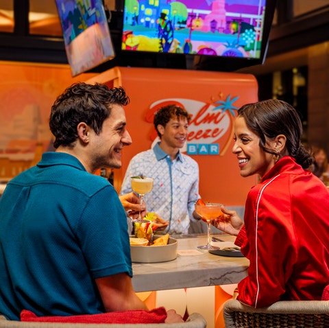 A smiling couple enjoying a beverage at Palm Breeze Bar in the Disneyland Hotel
