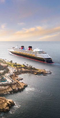 An aerial view of La Jolla Cove with a Disney cruise ship sailing along the coastline in California