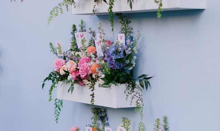 A floral wall display with tiered shelves of colorful blooms next to text reading, Happily Ever After