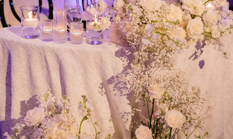 A sweetheart table surrounded by cascading roses, hydrangeas and baby's breath